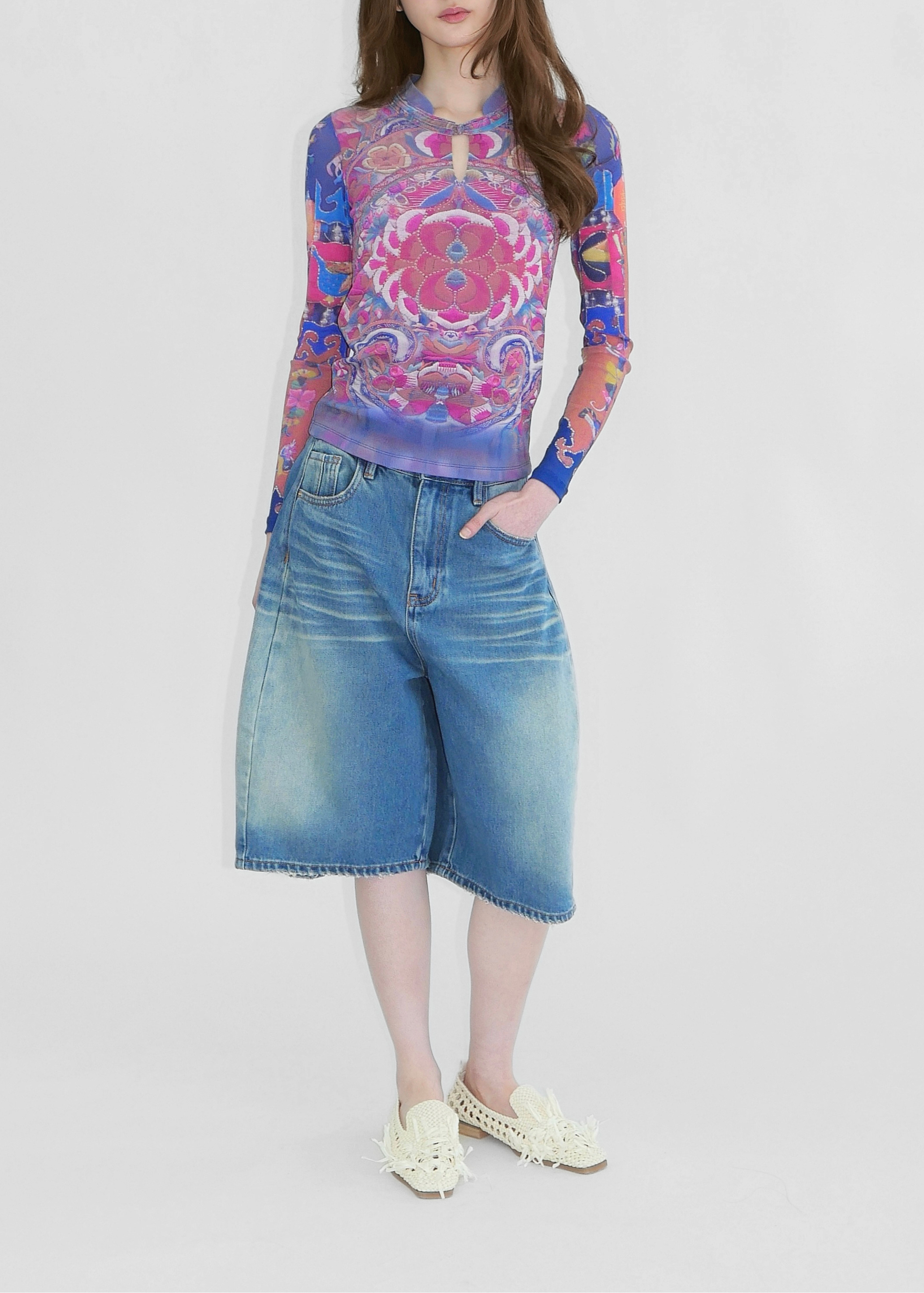 A model wearing Chinese style print in blue and pink mesh top with madarin collar and chinese knot fastening and denim shorts
