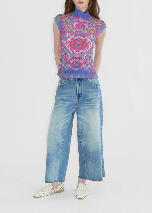Woman wearing a colorful sleeveless top and blue jeans on a white background