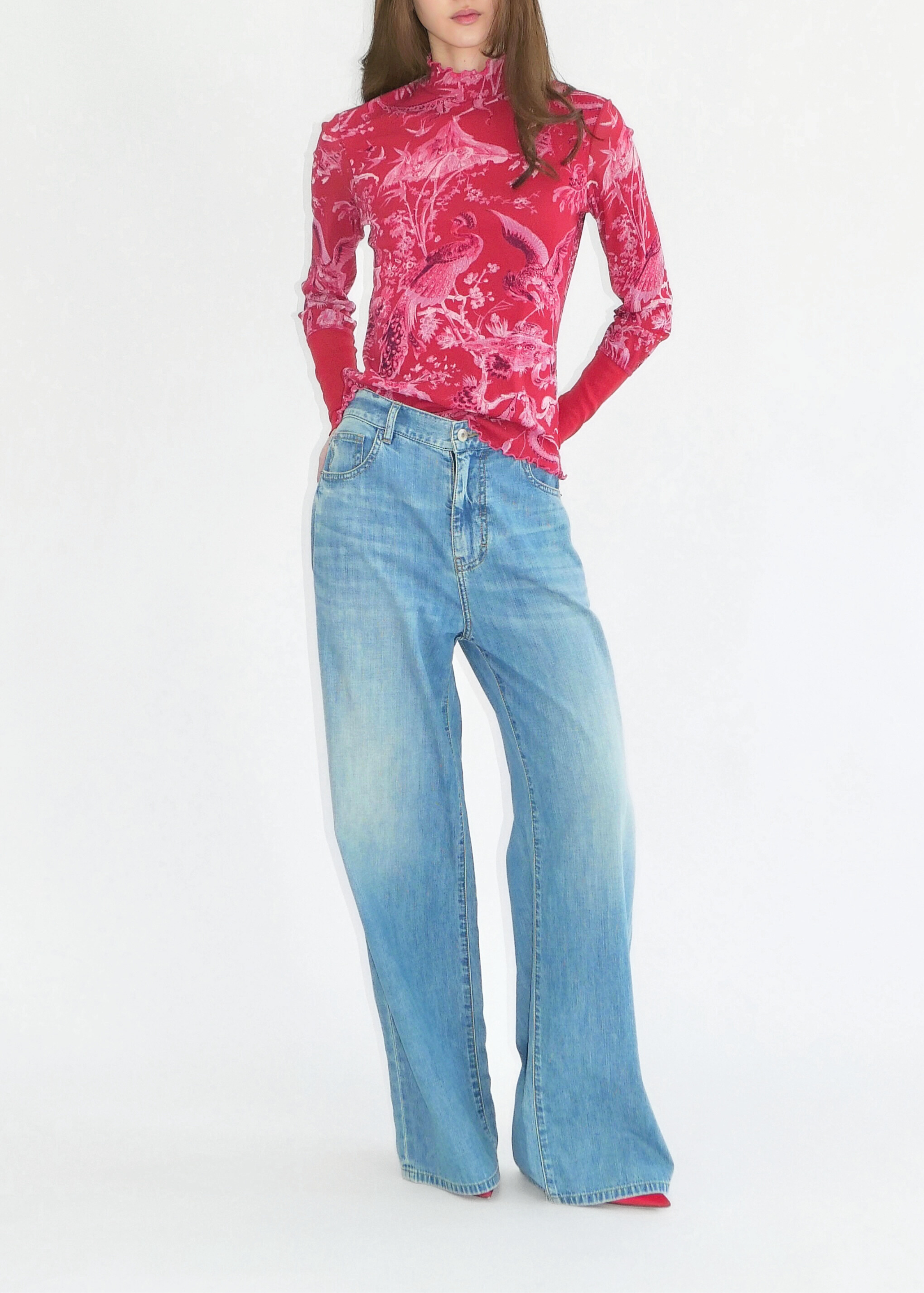 Person wearing a pink print top and blue jeans on a white background
