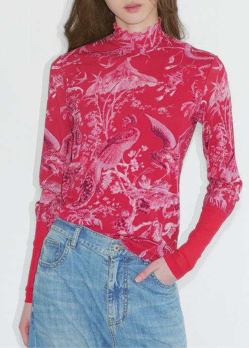 Person wearing a red patterned long-sleeve top and blue jeans on a white background