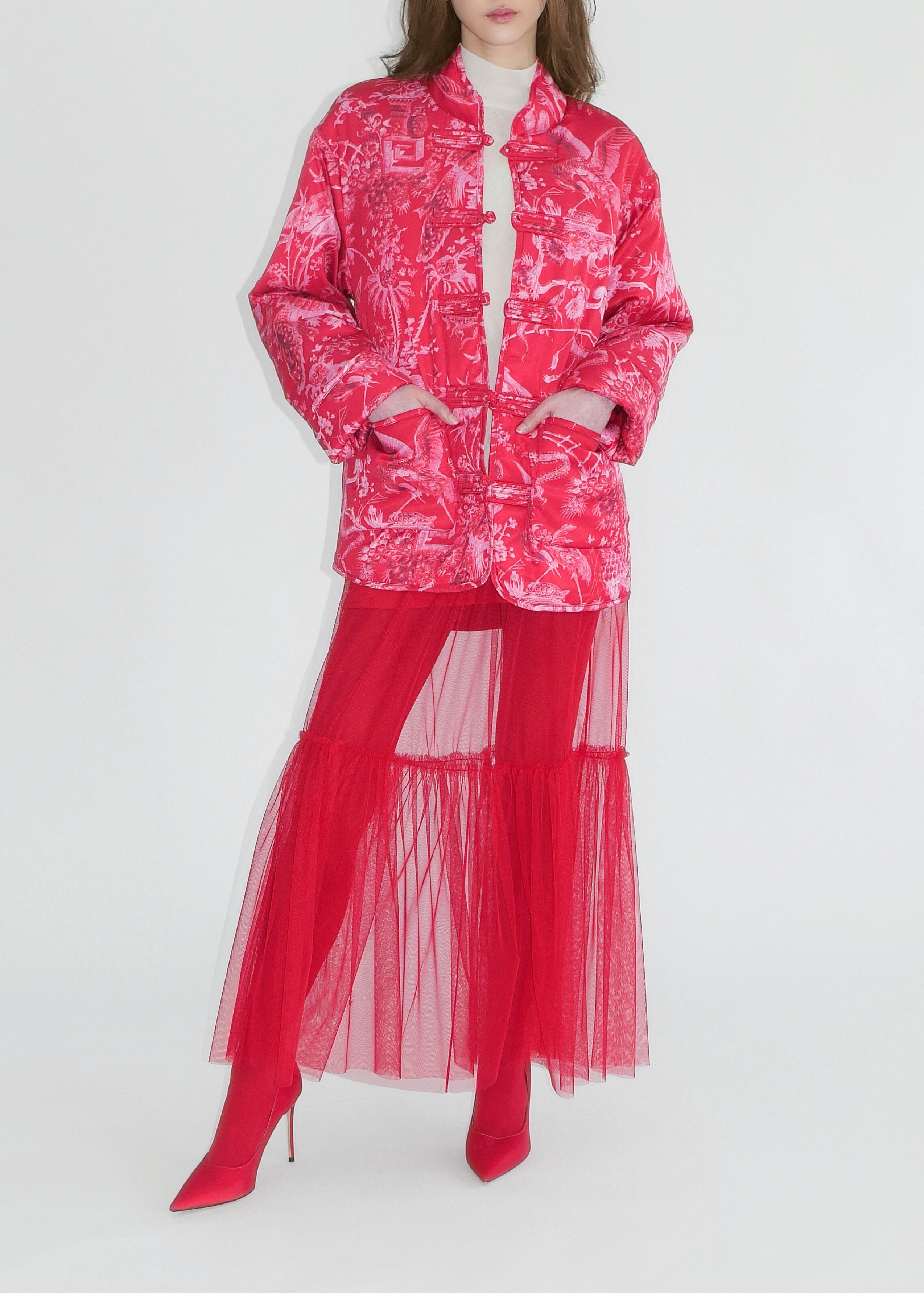 Person wearing a bright pink outfit with a matching jacket and red skirt on a white background
