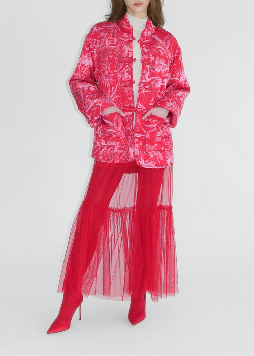 Person wearing a bright pink outfit with a matching jacket and red skirt on a white background