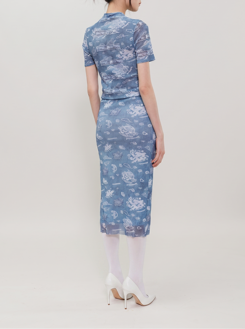 A woman is shown from the back wearing a short-sleeve blue dress with a white floral and cloud pattern, paired with white tights and white high heels, against a plain light gray studio background.