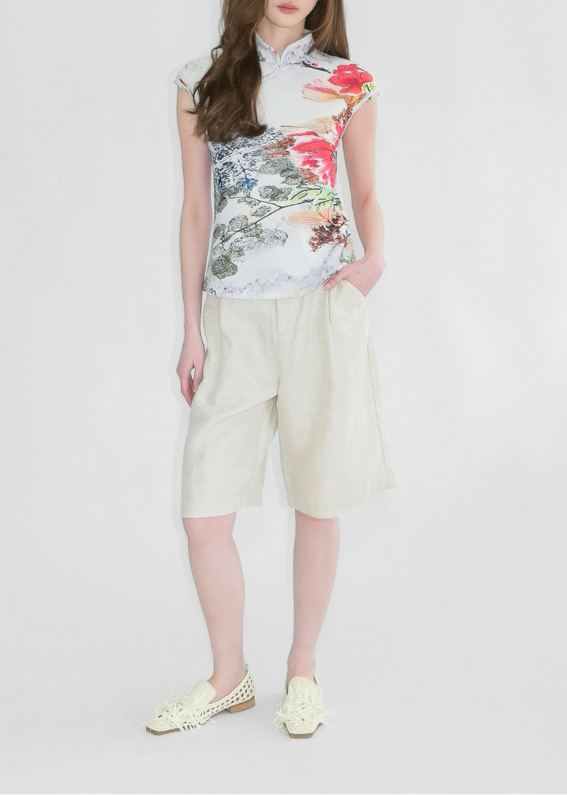 Woman wearing a floral top and light-colored pants on a white background