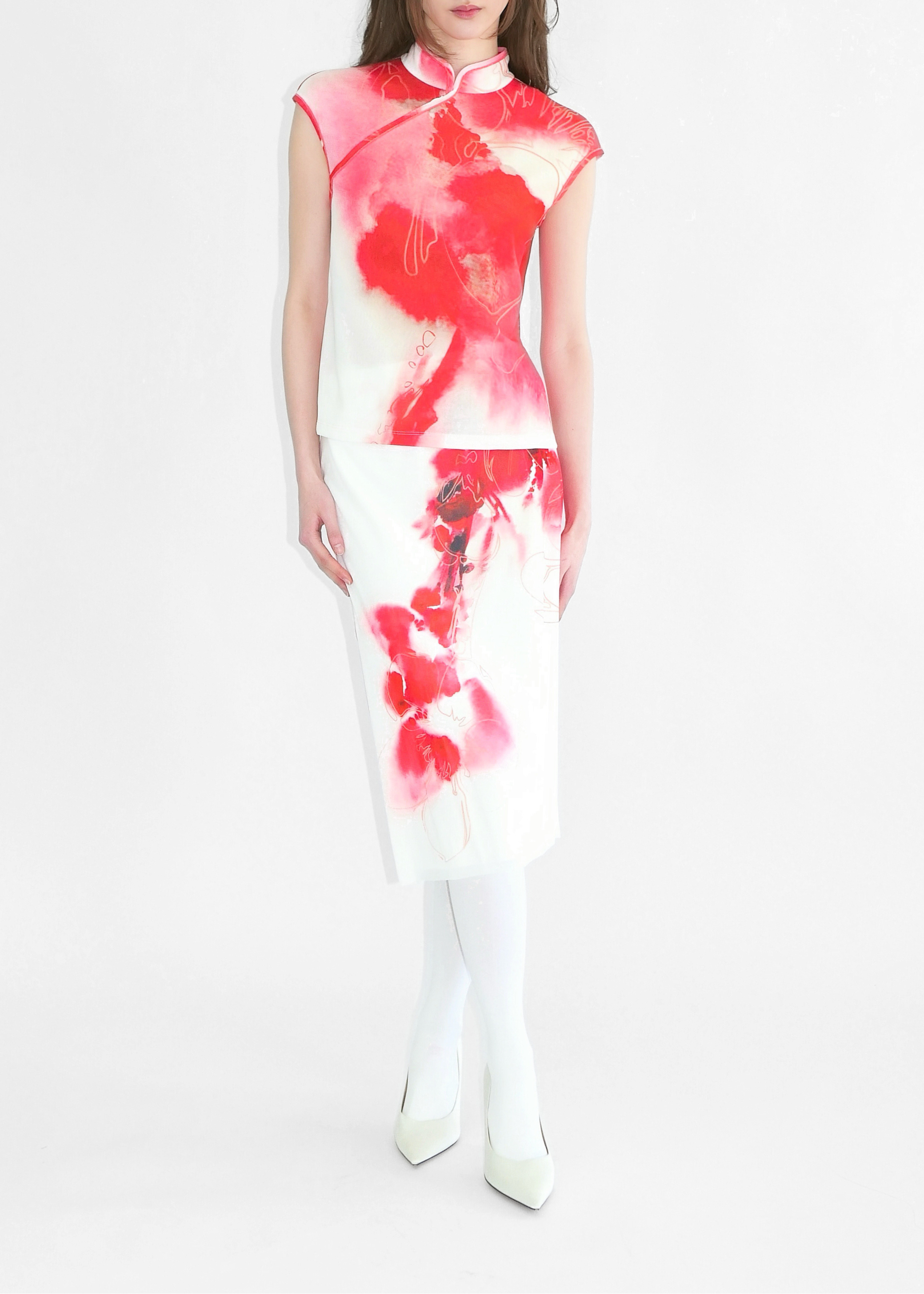 Model wearing a white dress with red floral patterns on a white background