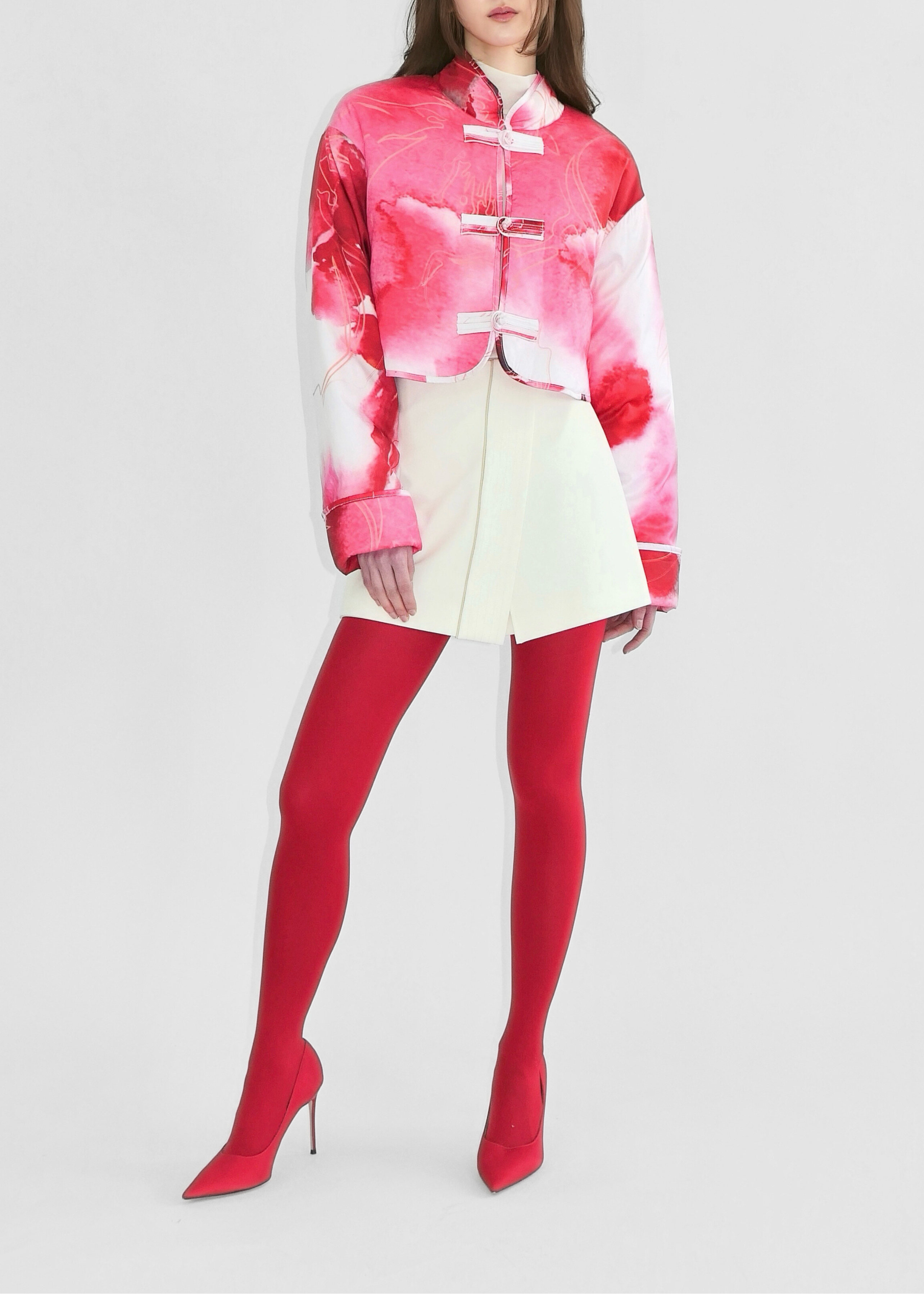 Person wearing a colorful jacket, white skirt, and red tights on a white background