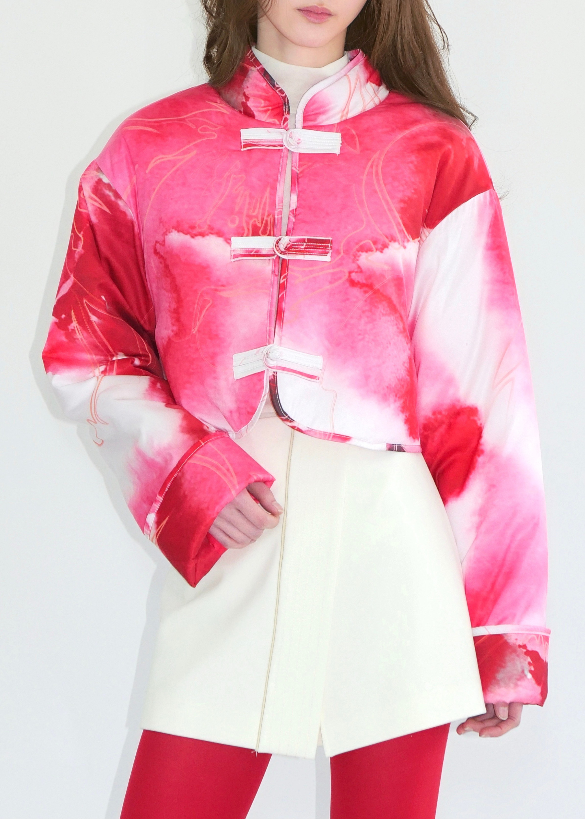 Person wearing a pink and white tie-dye jacket on a plain background