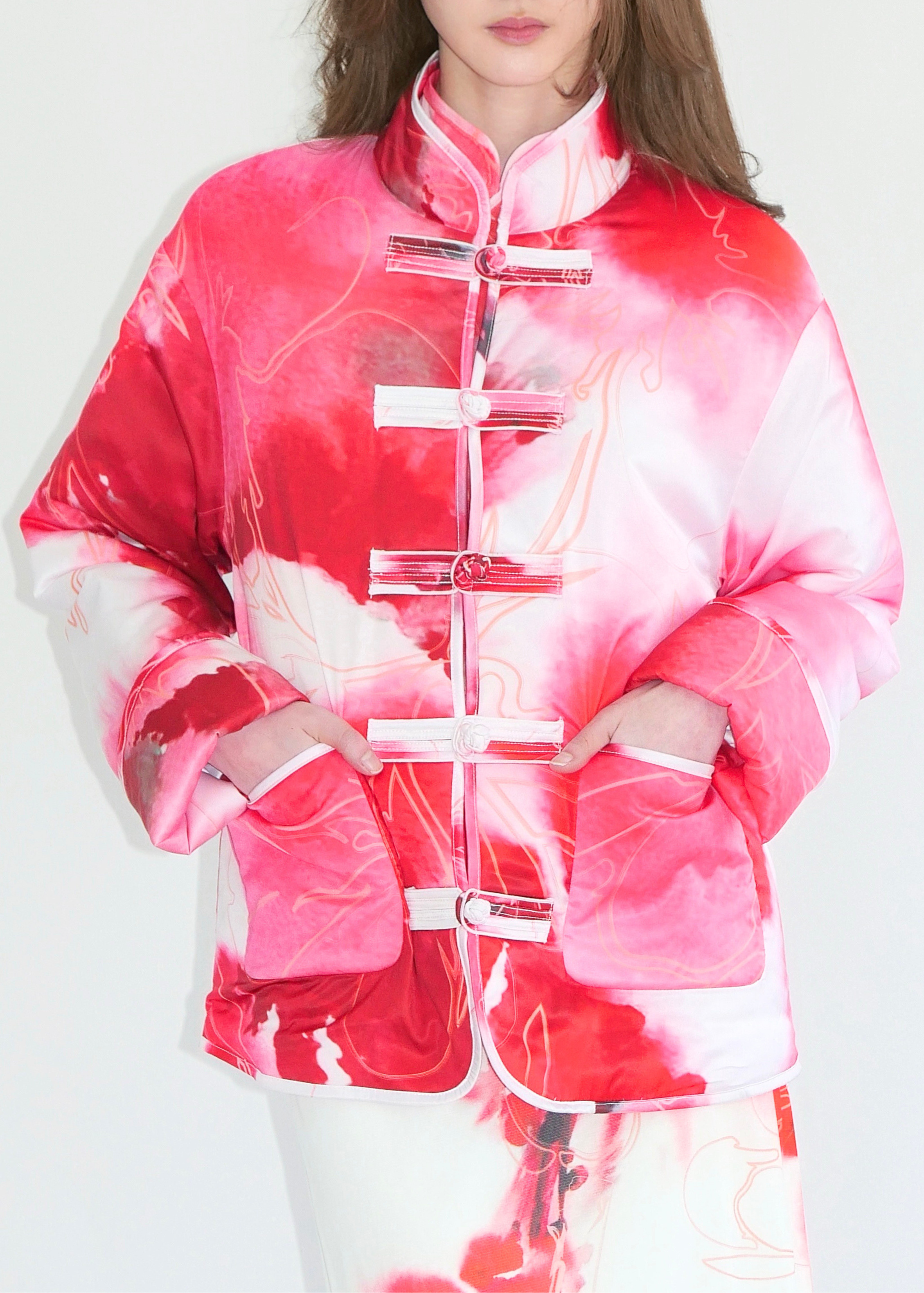 Person wearing a red and white tie-dye outfit on a plain background