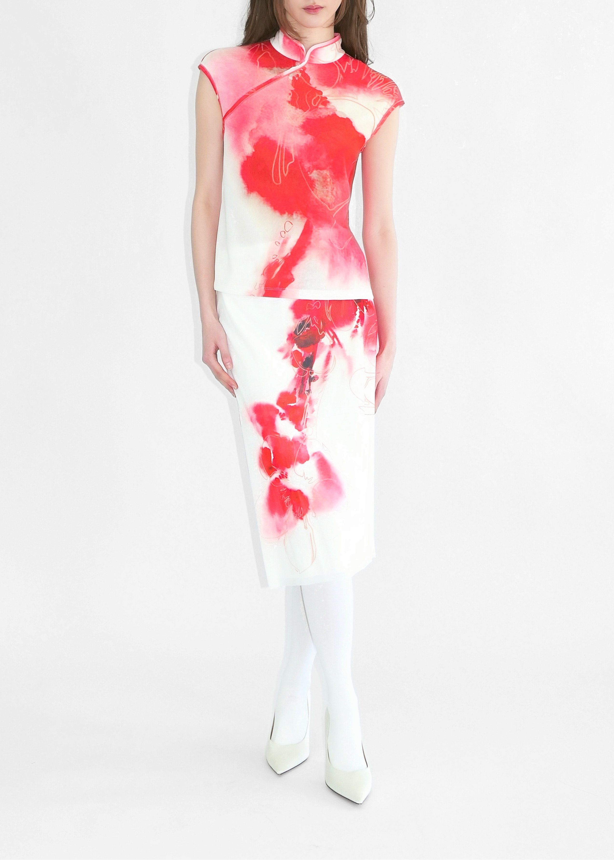 Model wearing a white dress with red floral patterns on a white background