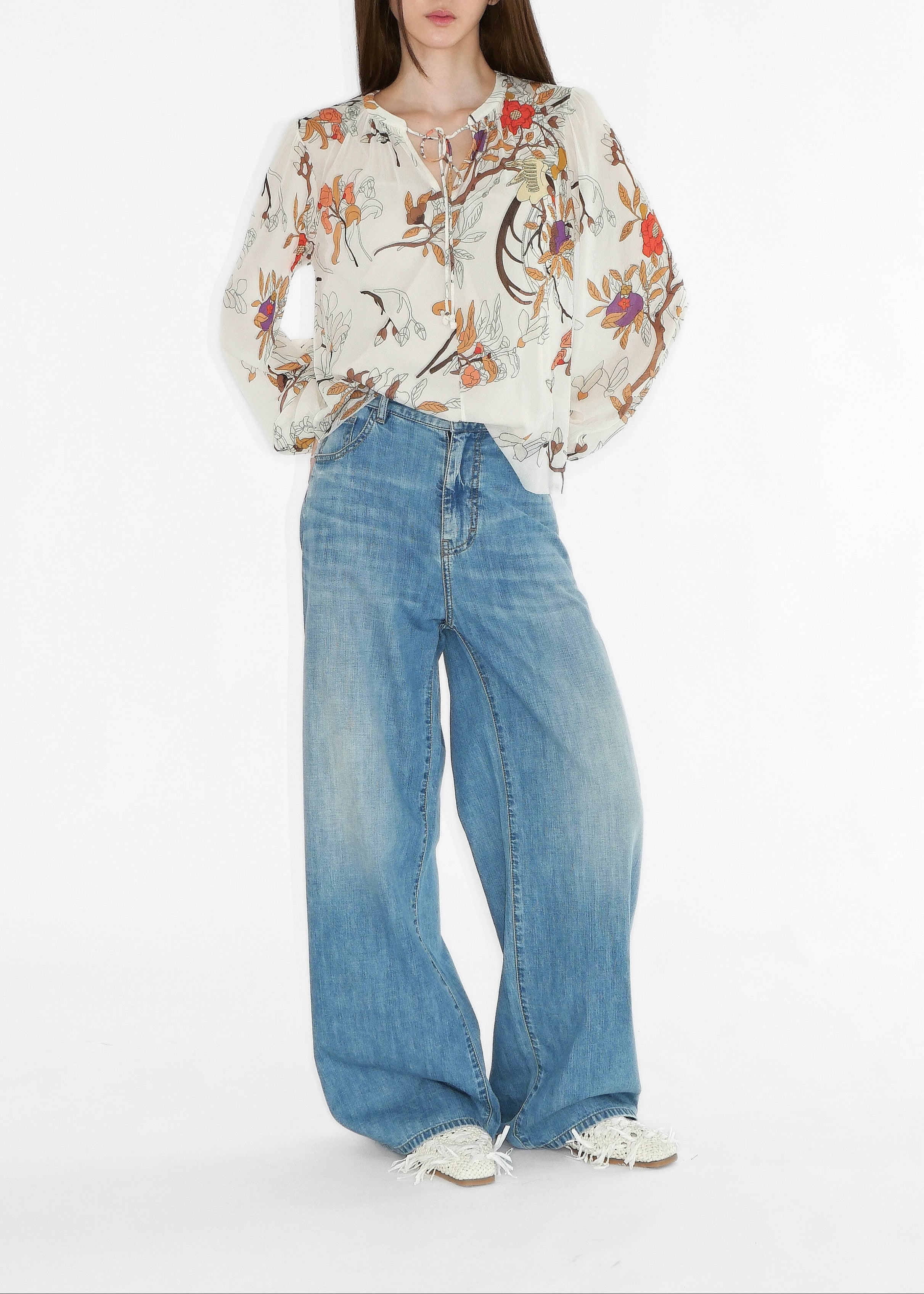 Person wearing a floral blouse and blue jeans on a white background