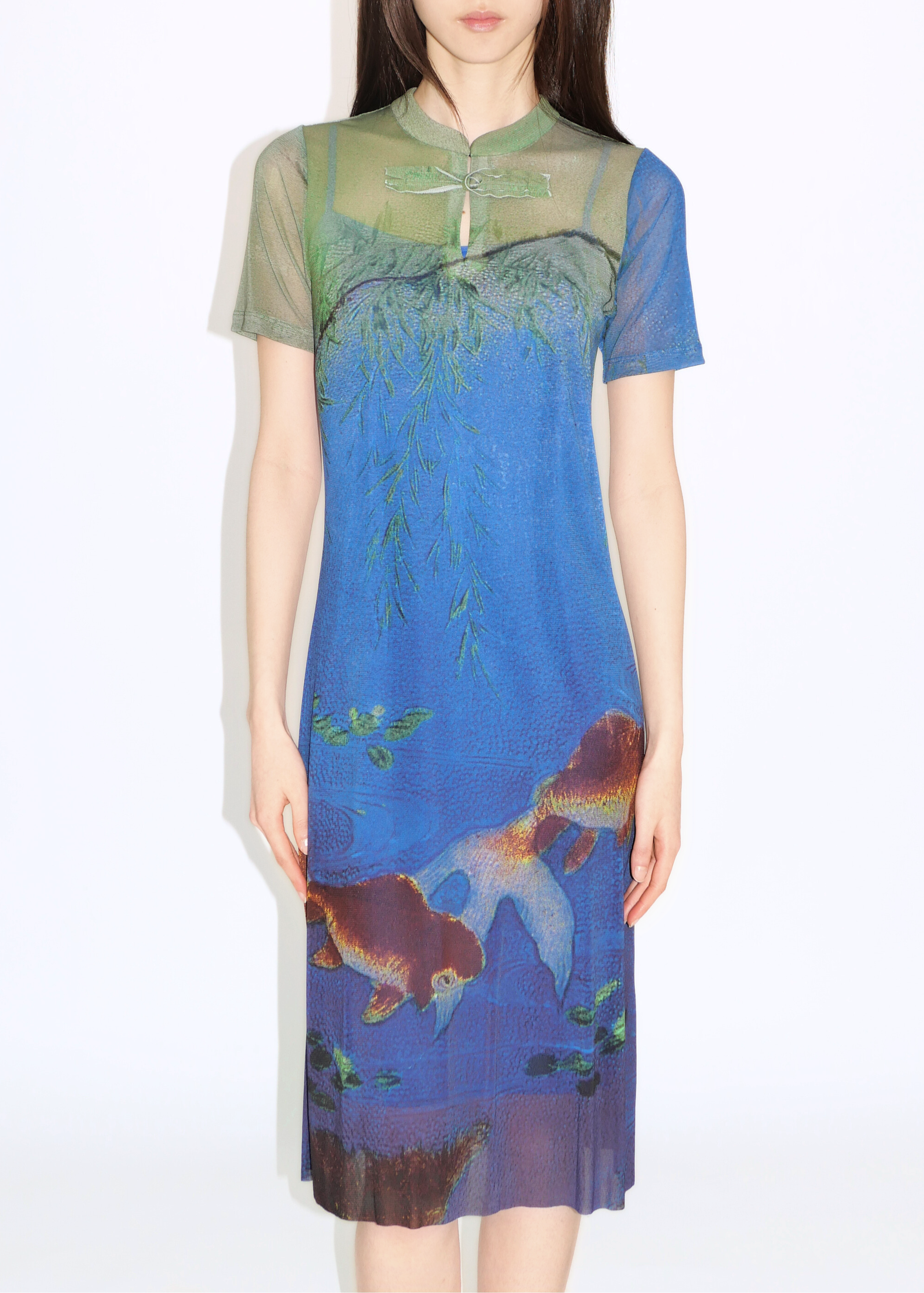 A woman wearing a blue and green floral netting cheongsam dress with a mandarin collar.