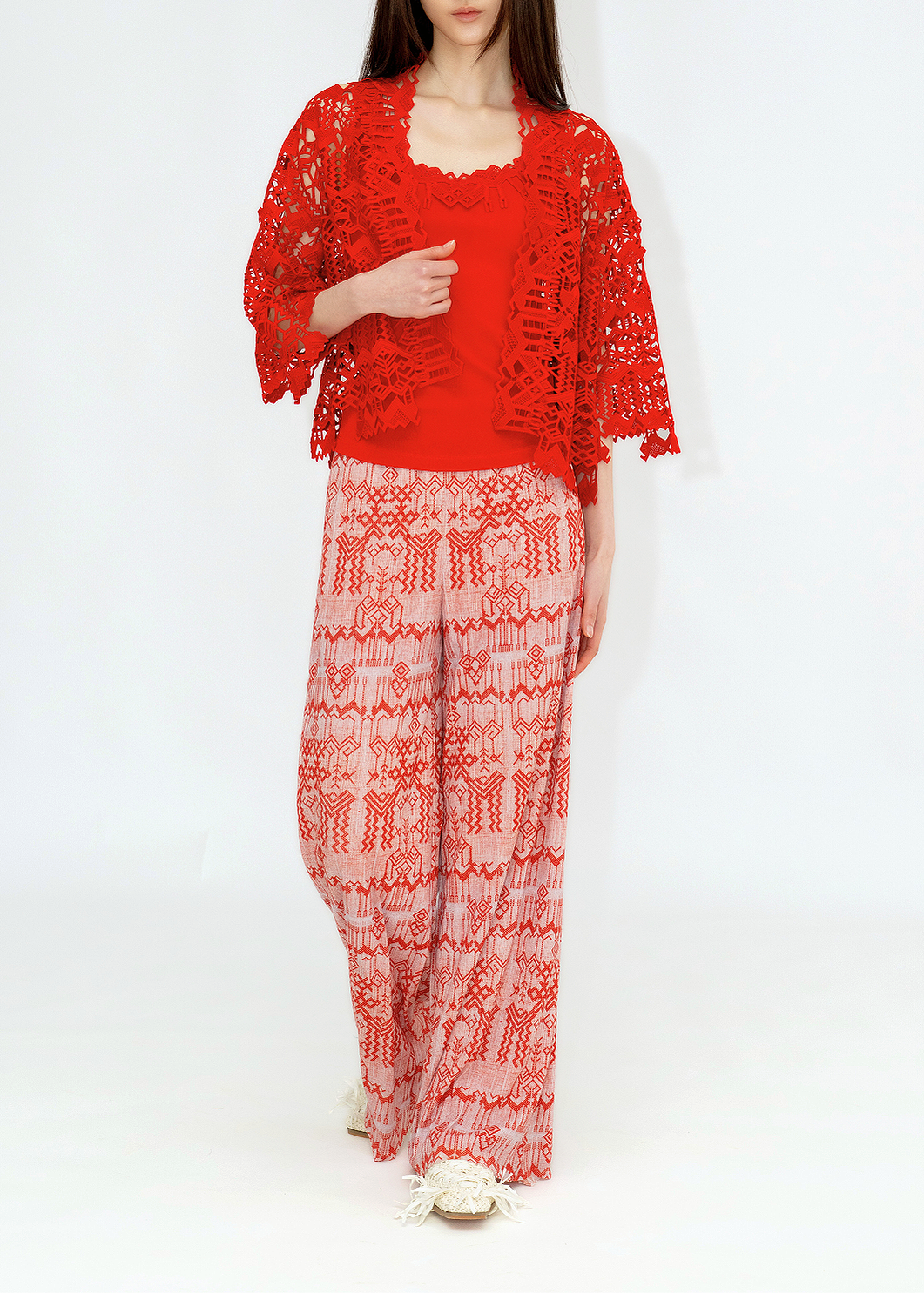 A woman wearing a red deer lace cardigan and matching red pants with a leaf pattern.