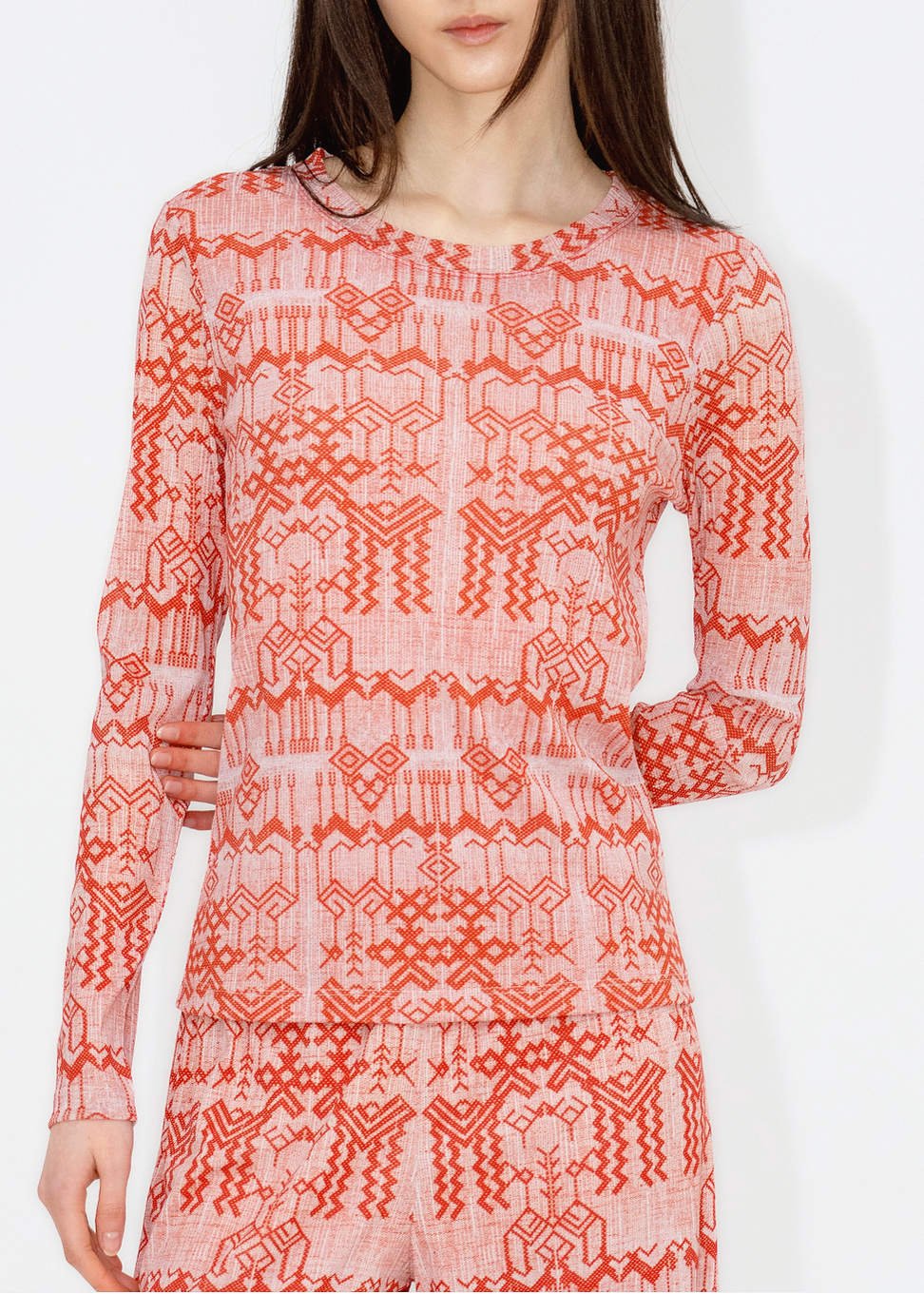 A woman wearing a red and white deer print top with long sleeves.