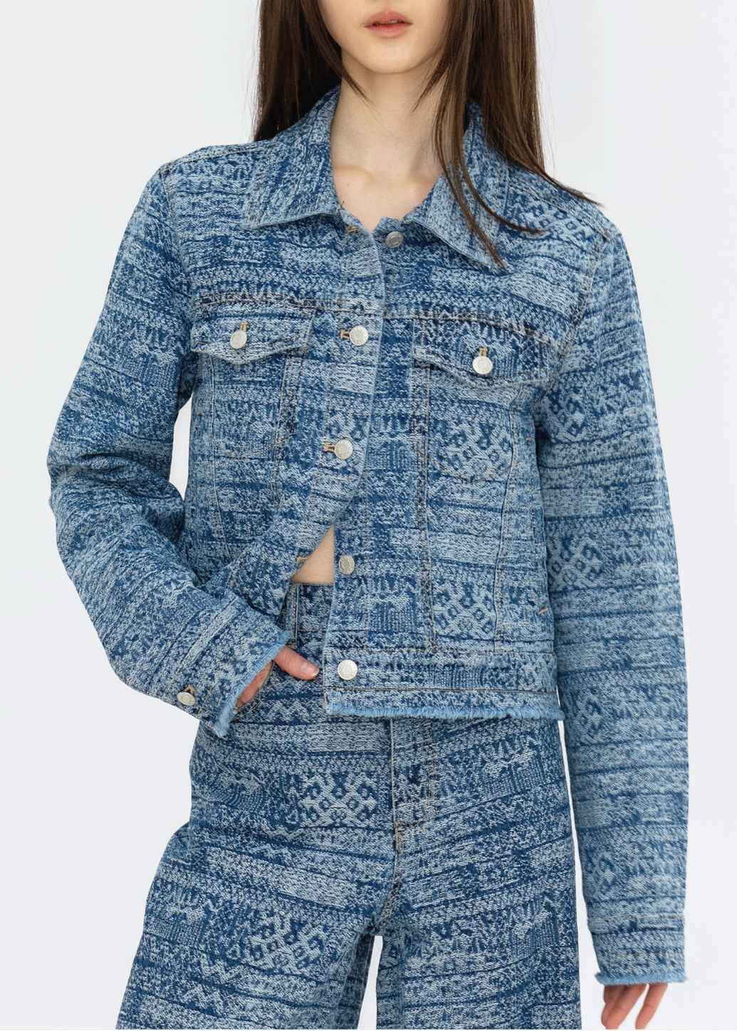 A woman wearing a blue tie-dye stripe denim jacket with long sleeves and button closures. The jacket has a collared neckline and is paired with a similar patterned denim skirt.