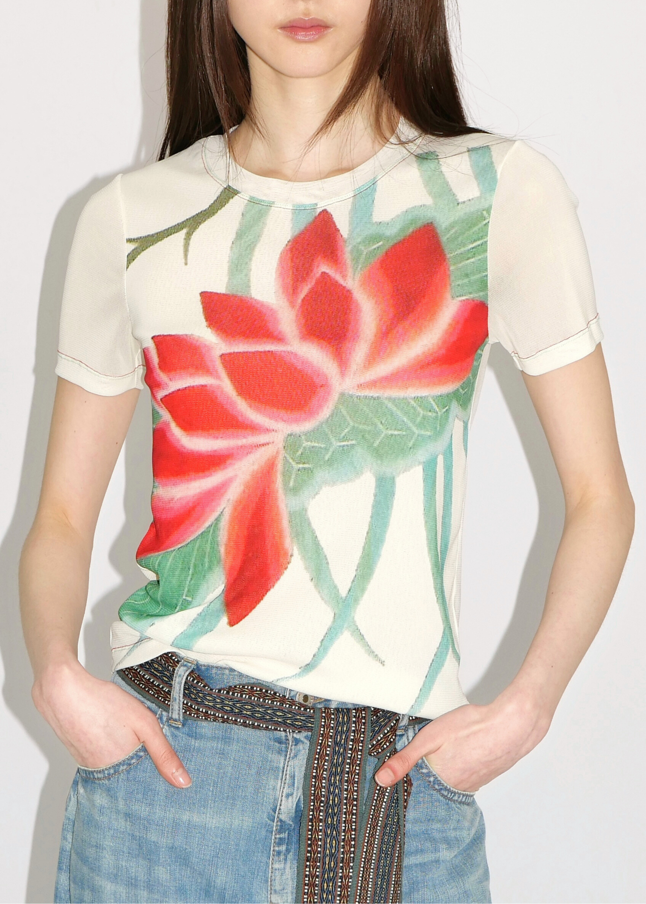 Woman wearing a t-shirt with a red floral design on a plain background