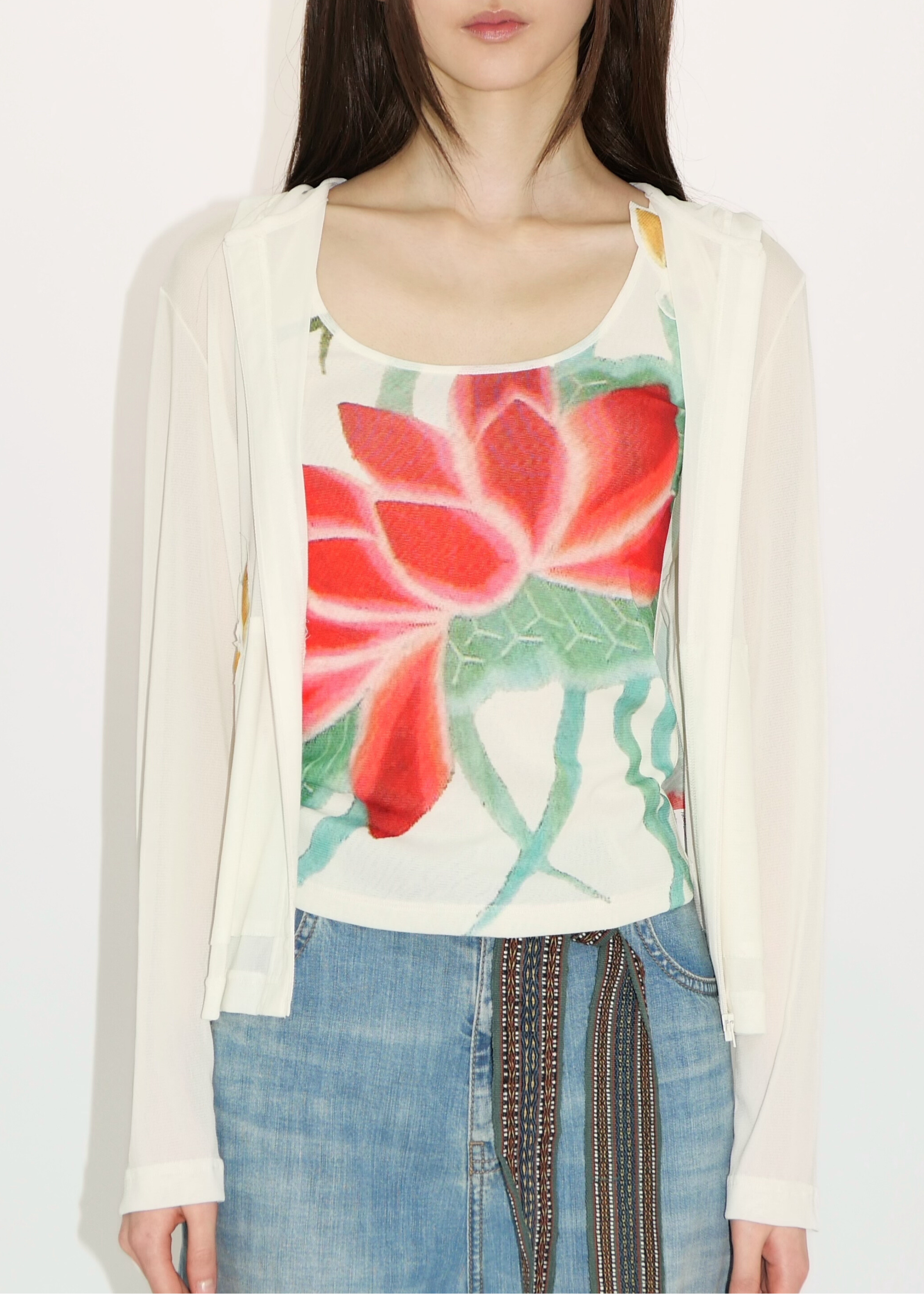 Woman wearing a floral top and cardigan with a plain background