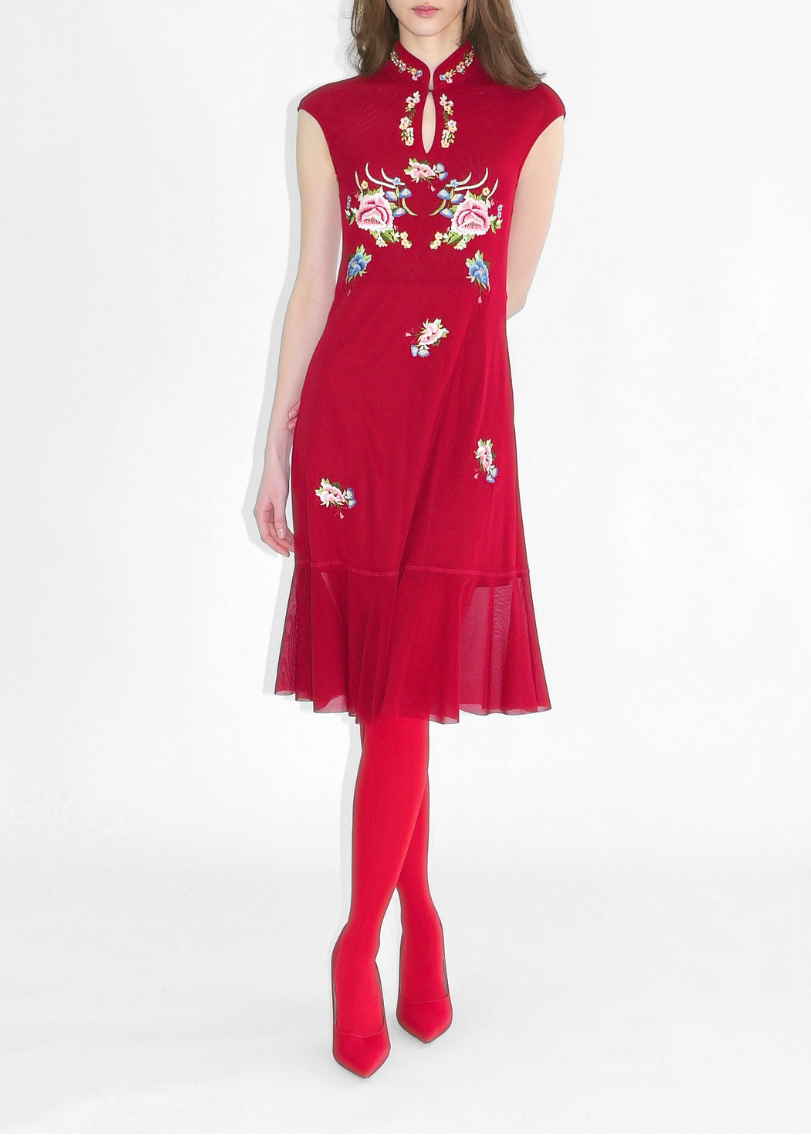 Woman wearing a red dress with floral embroidery on a white background