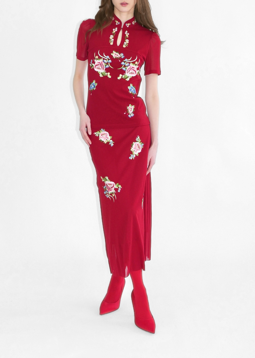 Woman wearing a red dress with floral embroidery on a white background
