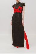 A model stands against a plain light gray studio background wearing a dark brown textured cheongsam-style dress with a bright red embroidered chest motif and a red slit at the hem.