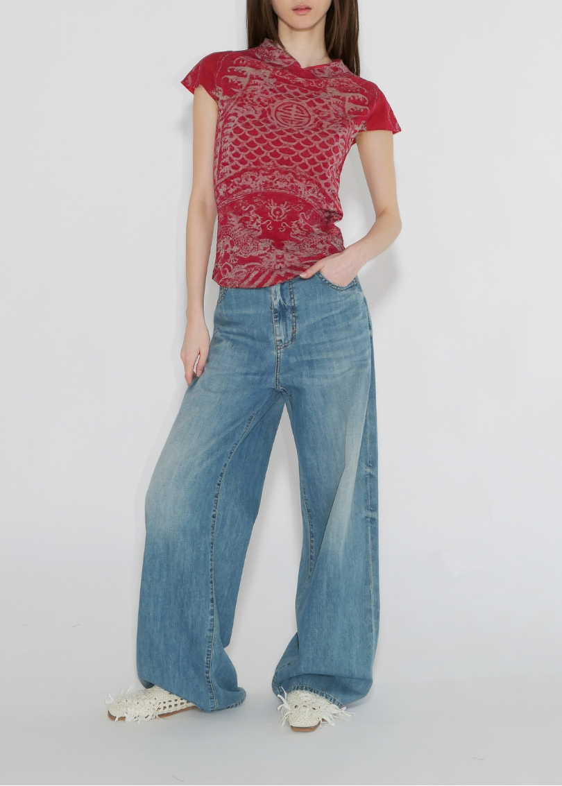 Person wearing a red patterned top and blue jeans on a white background