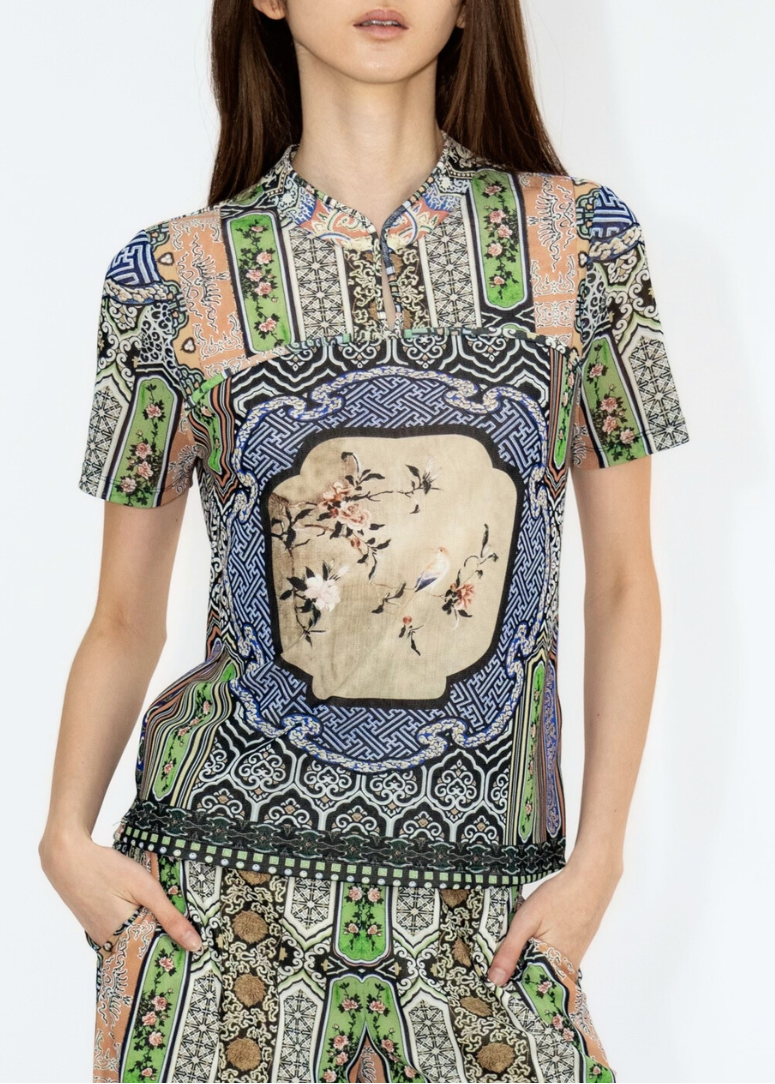 Model wearing a patterned dress with intricate designs on a white background