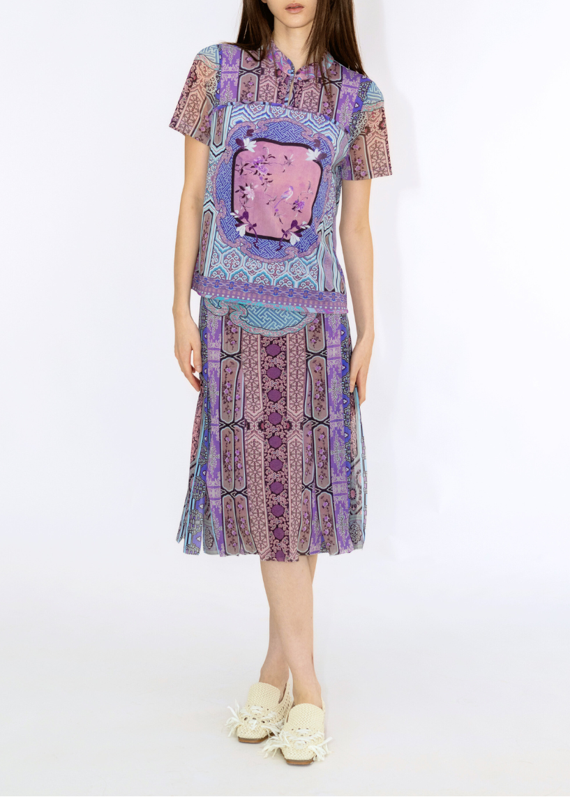 Woman wearing a colorful outfit with a patterned top and skirt on a white background
