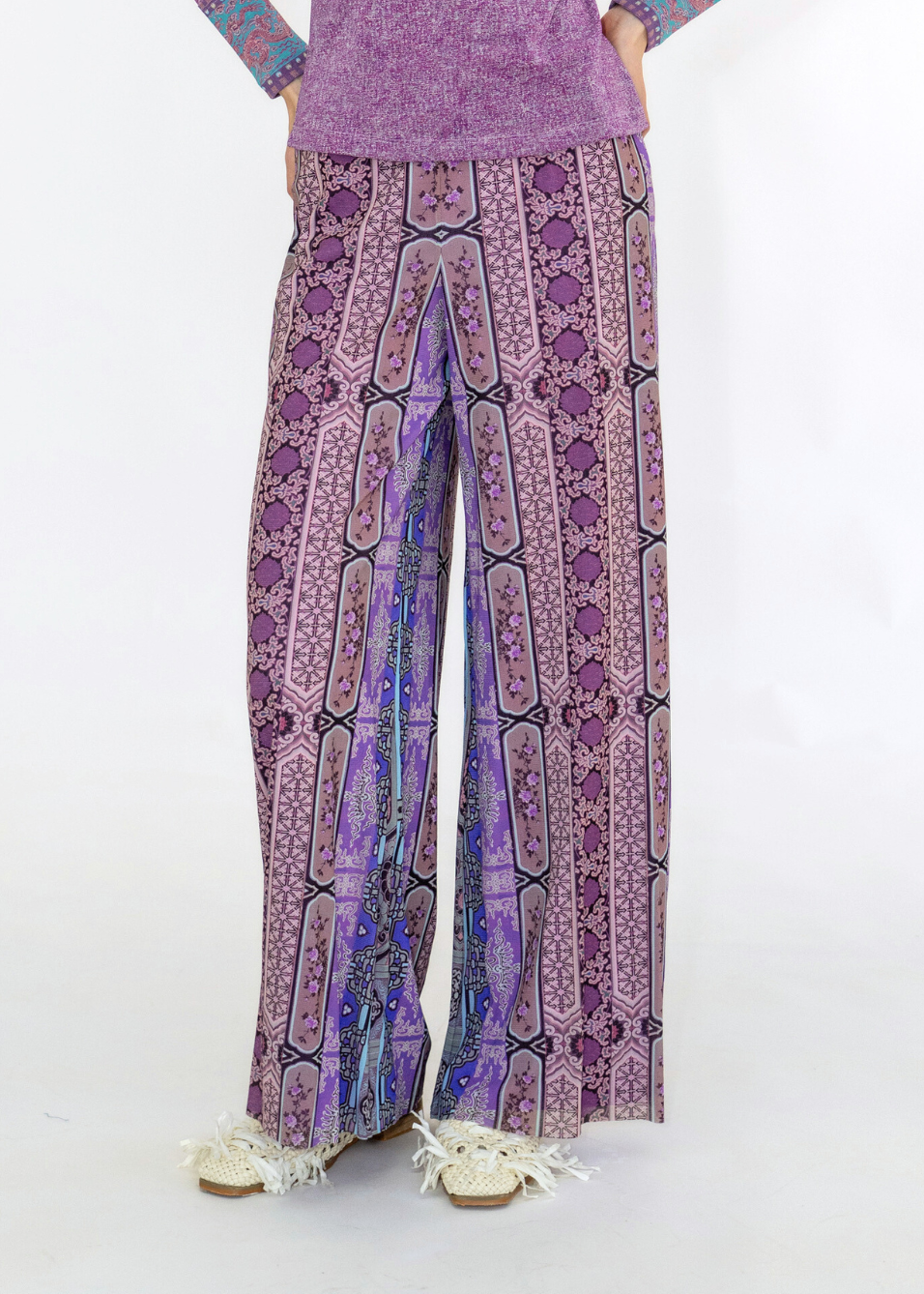 Purple patterned pants worn by a person on a white background