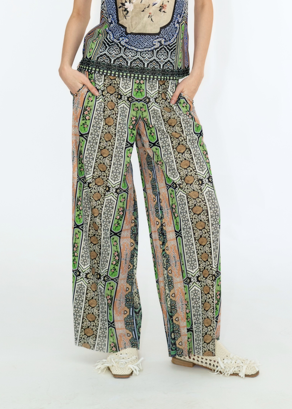 Person wearing a patterned outfit with wide-leg pants on a white background