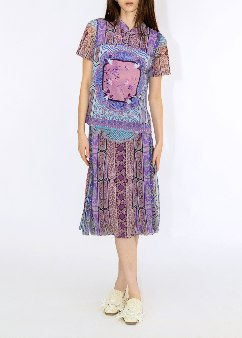 Woman wearing a colorful outfit with a patterned top and skirt on a white background