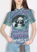 A woman wearing a multicolored traditional Chinese cheongsam top with a panda pattern, paired with blue jeans.