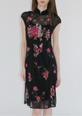 Woman wearing a black dress with colorful floral and abstract patterns on a white background