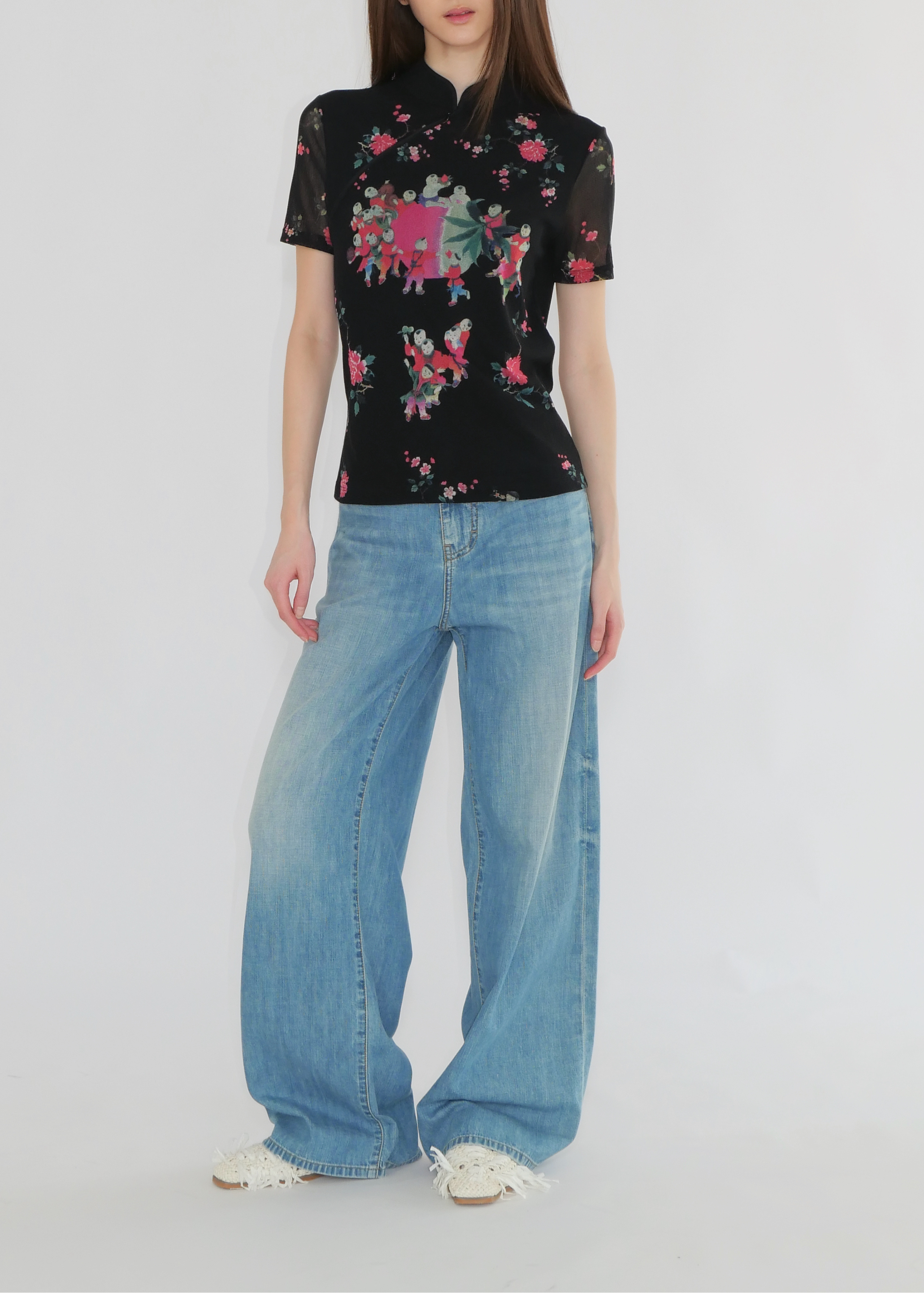 Person wearing a black floral shirt and blue jeans on a white background