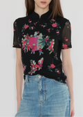 Woman wearing a black floral blouse with a plain background