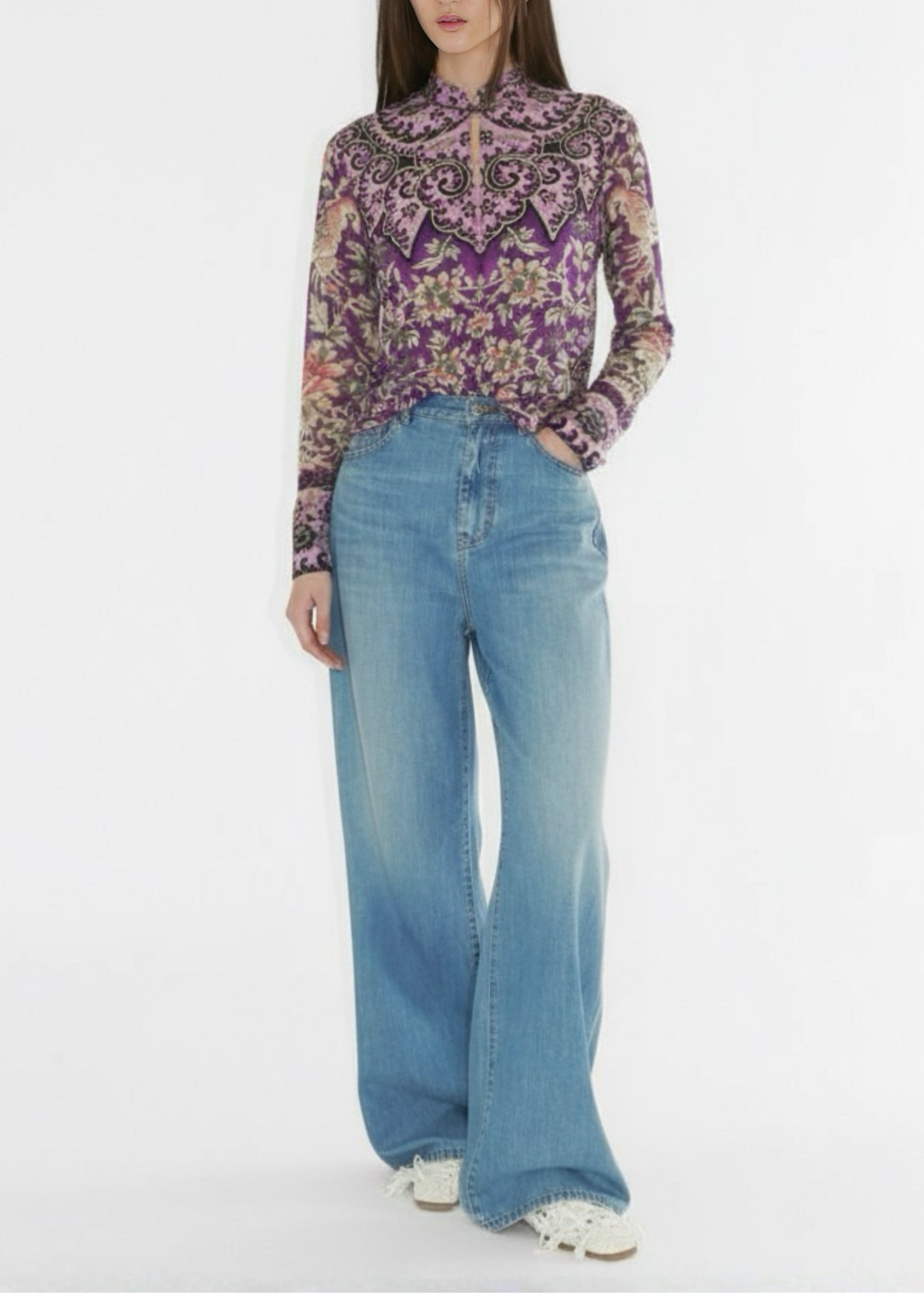 Person wearing a patterned shirt and blue jeans on a white background