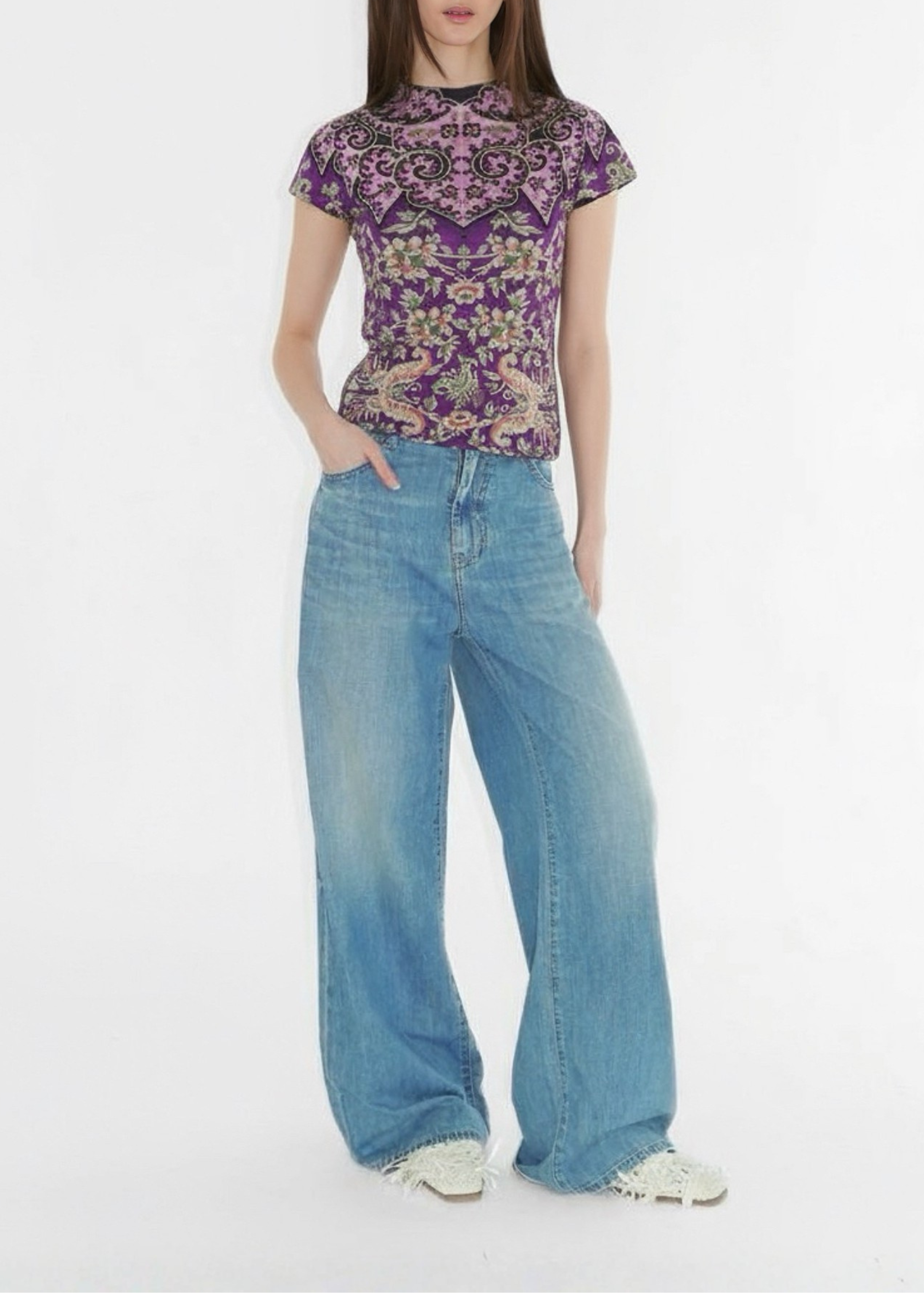Woman wearing a patterned top and blue jeans on a white background