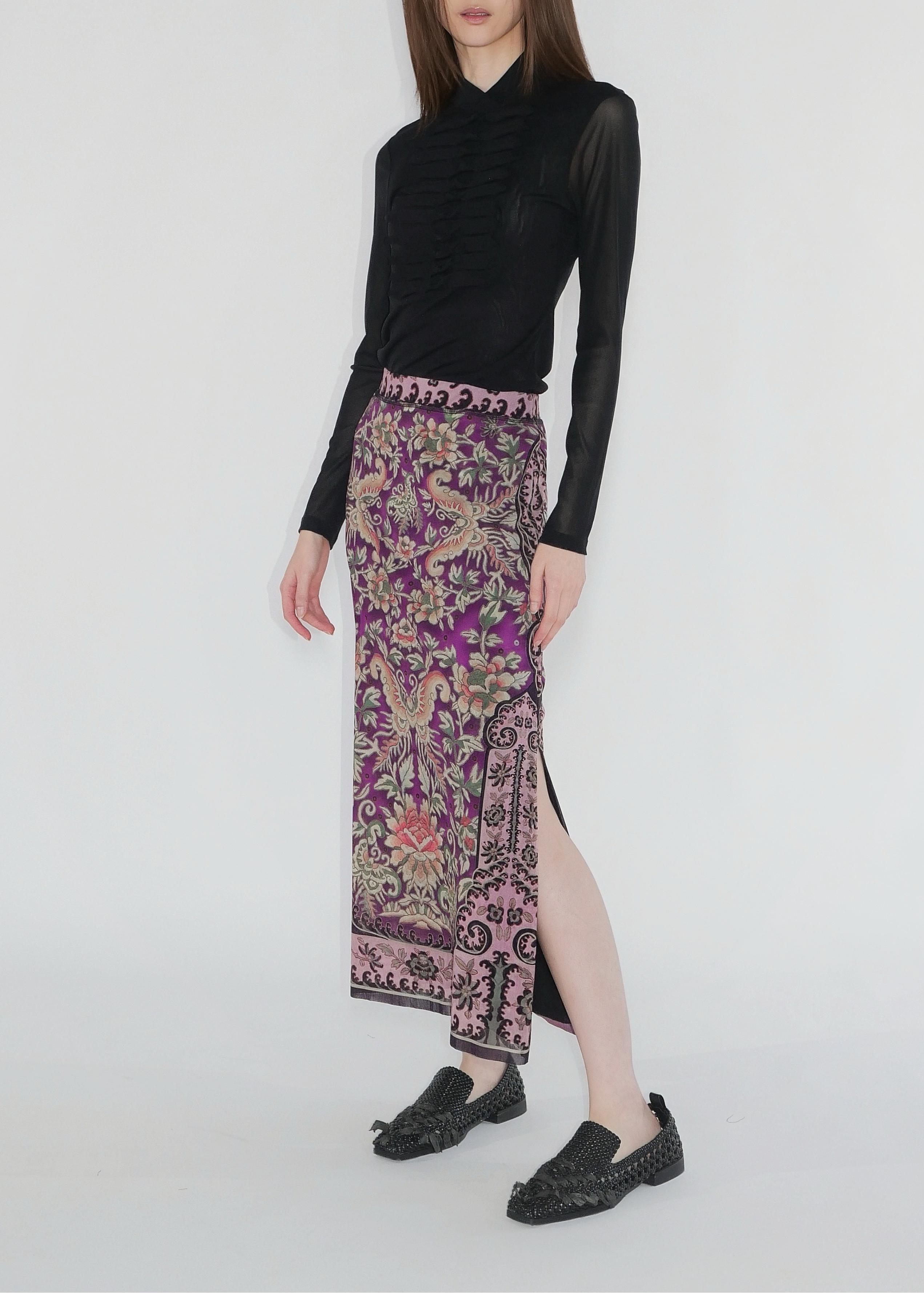 Woman wearing a black top and patterned skirt on a white background