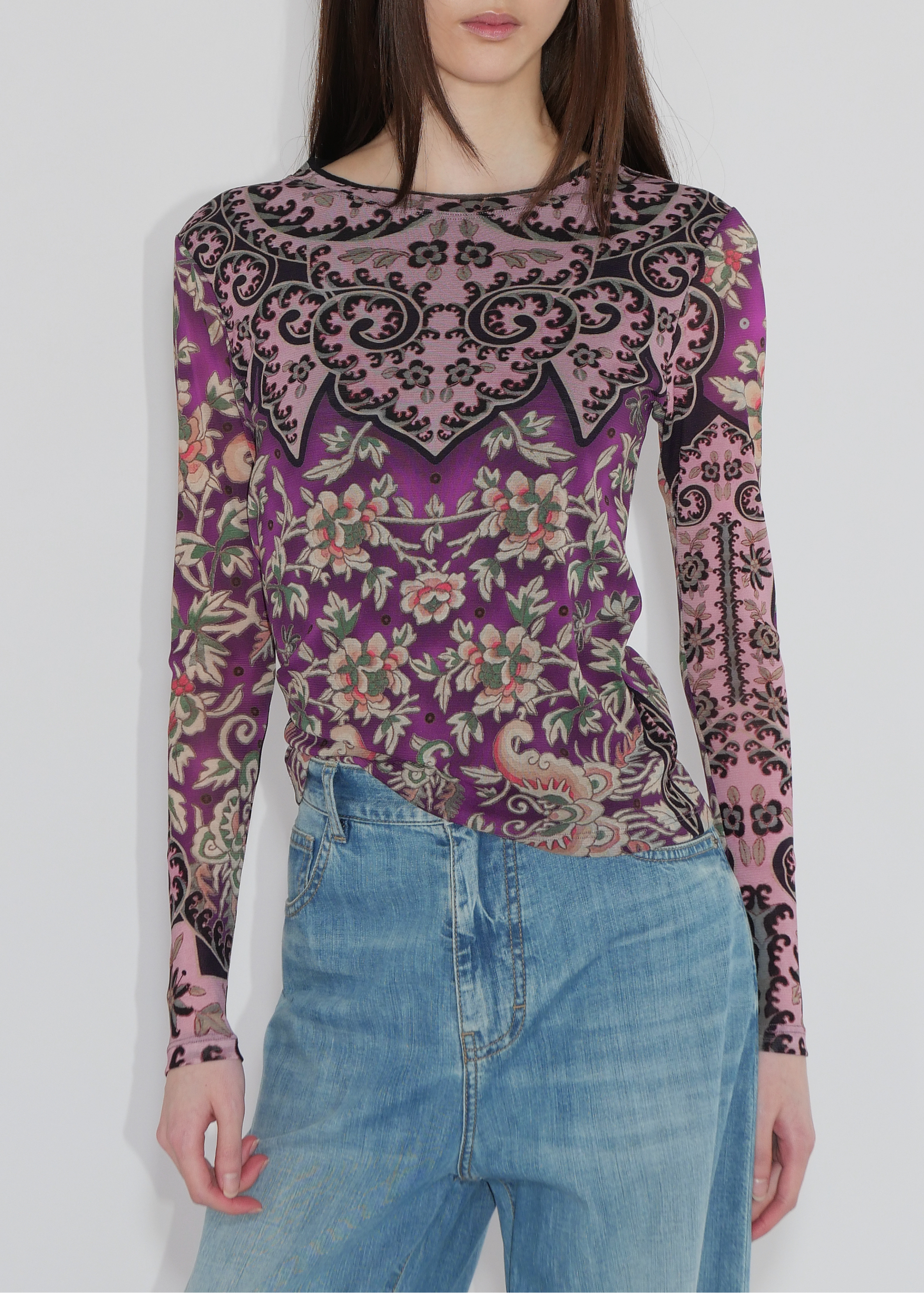 Woman wearing a long-sleeve top with a floral and paisley pattern on a plain background