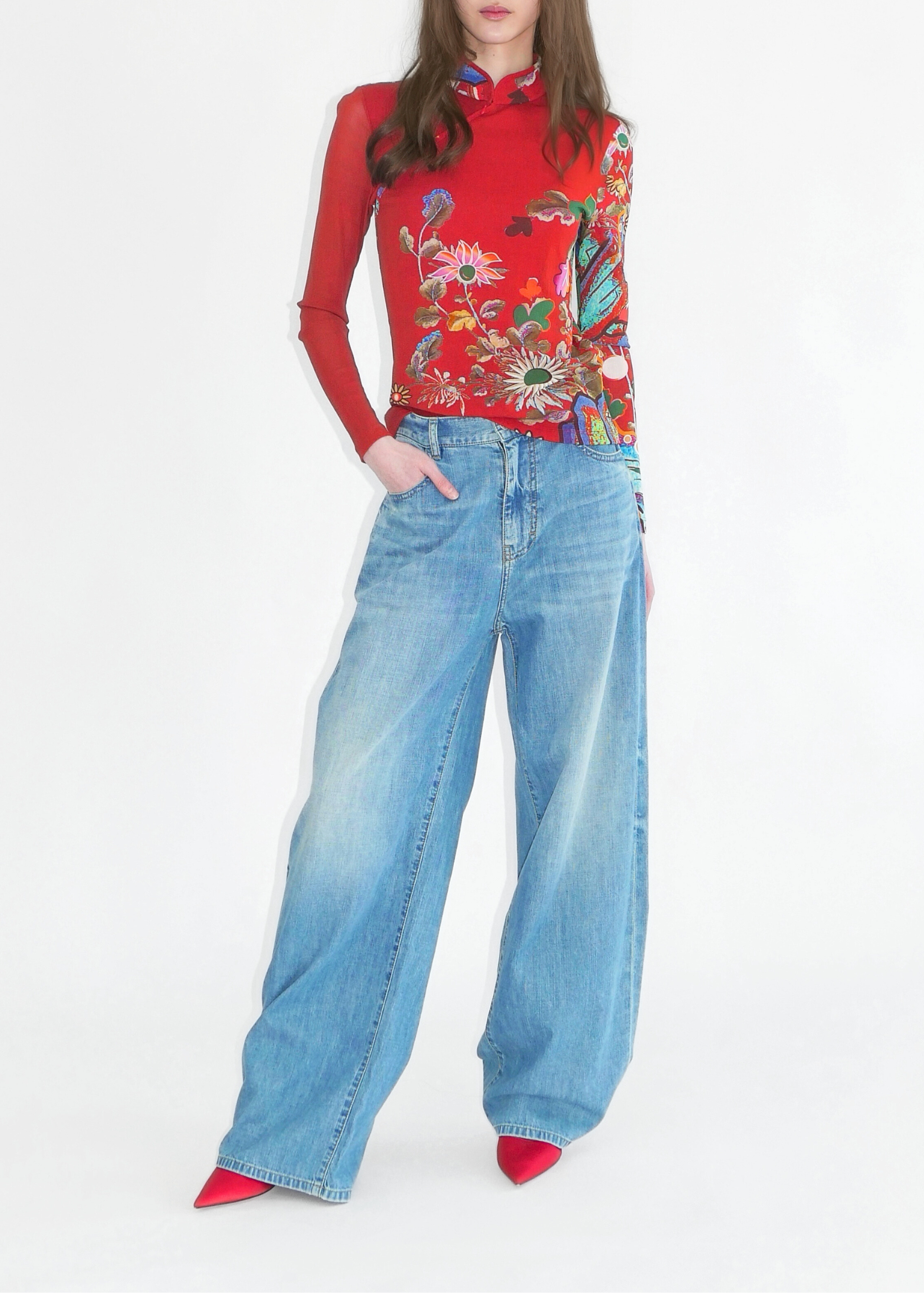 Woman wearing a red floral blouse and blue jeans on a white background