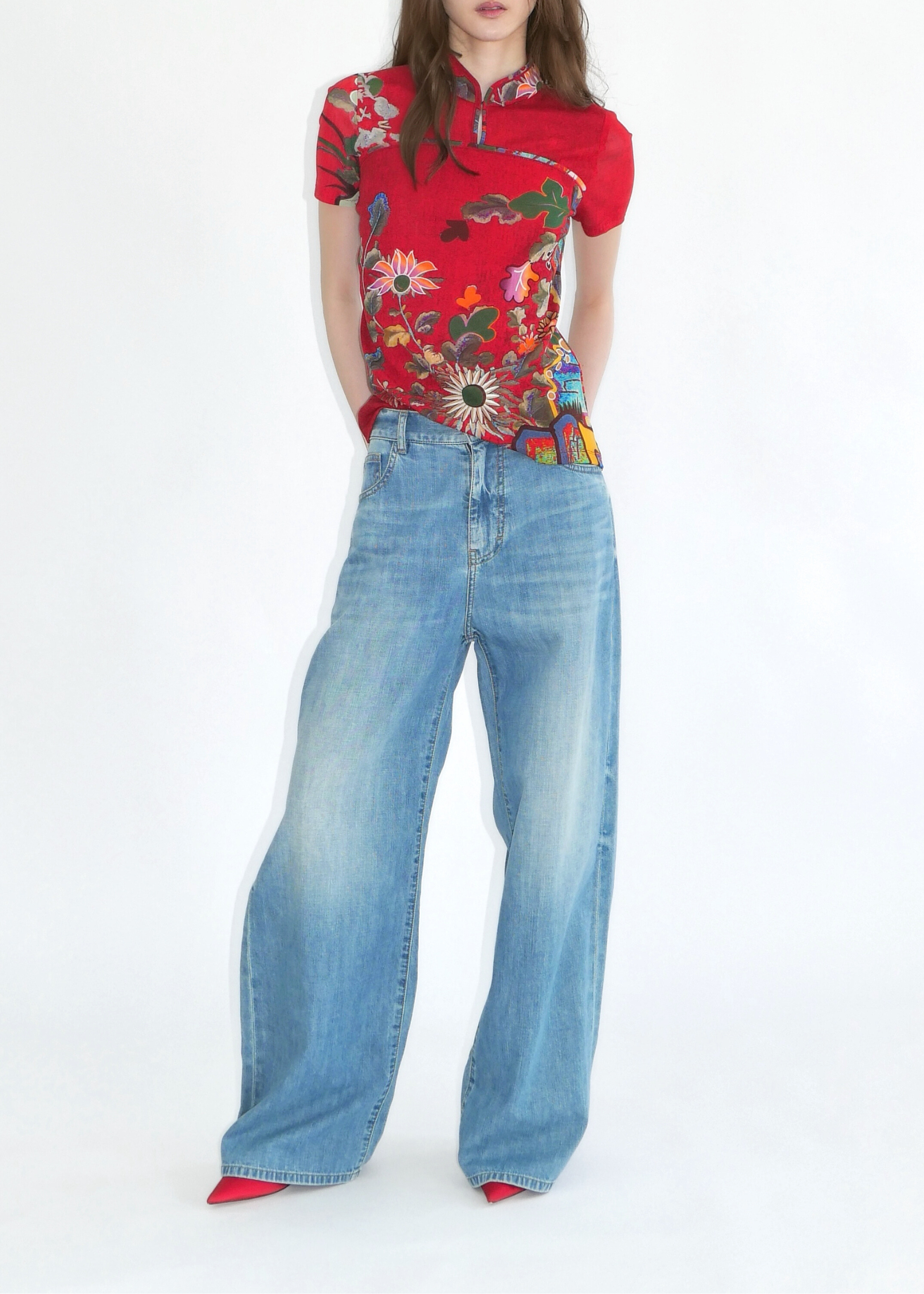 Woman wearing a red floral shirt and blue jeans on a white background