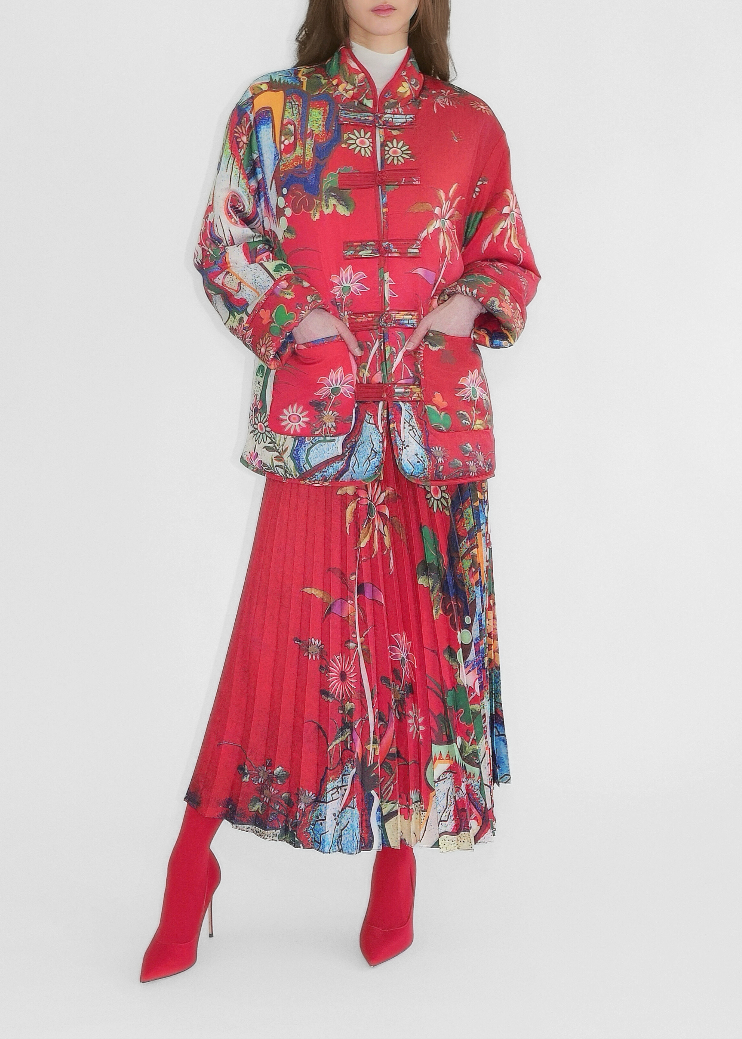 Woman wearing a colorful outfit with a red jacket and pleated skirt on a white background