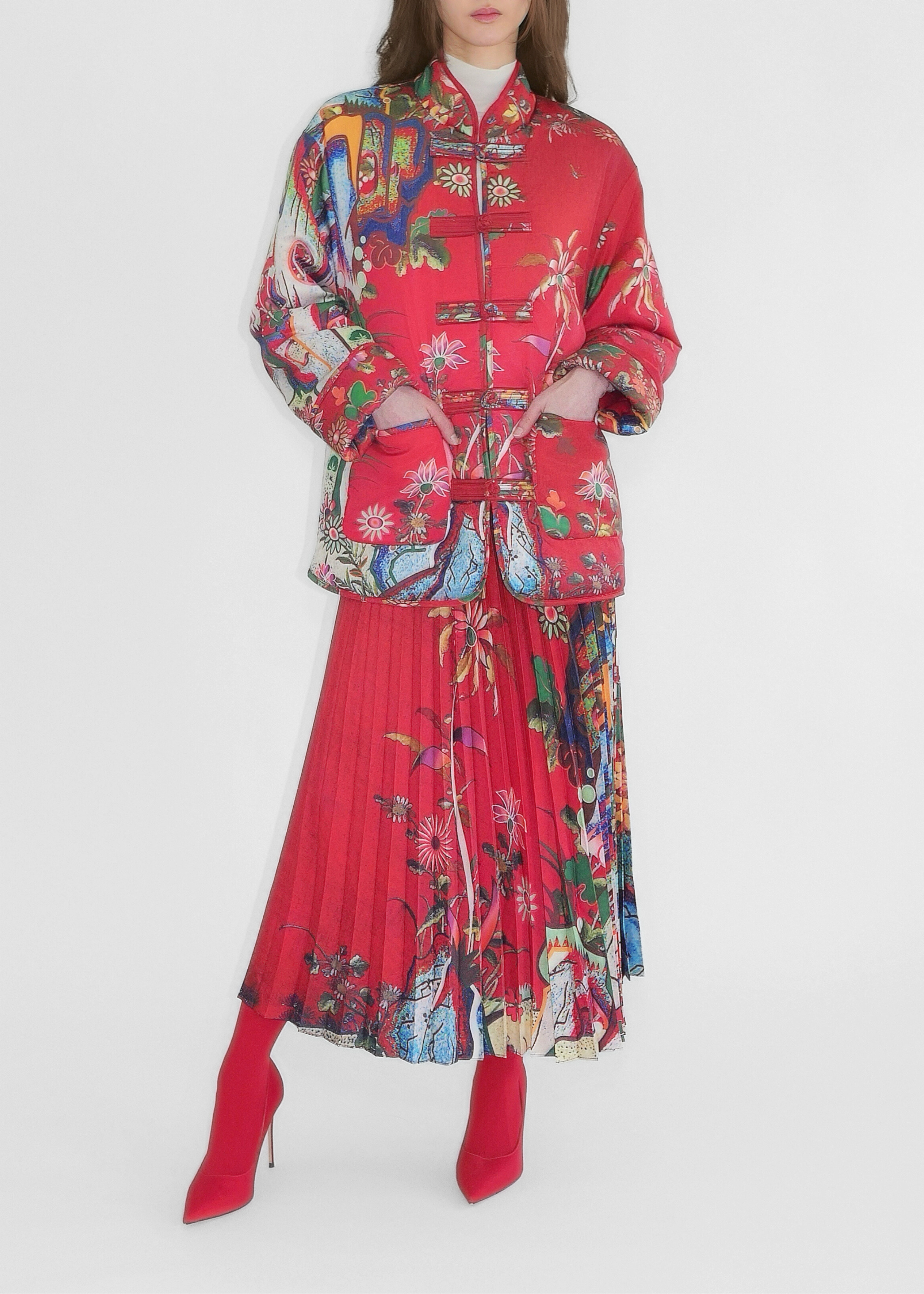 Woman wearing a colorful outfit with a red jacket and pleated skirt on a white background